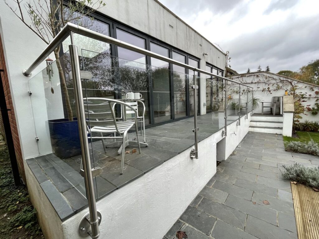 Epsom glass and glazing - an image of  a bespoke external glass balustrade produced and installed by Hamilton Glass Products Ltd - featuring the post and panel system with handrail.
