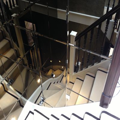 Quality bespoke mirrors - this image shows a beautiful stair way wall cladded in bronze tinted bevelled mirrors following the stair line