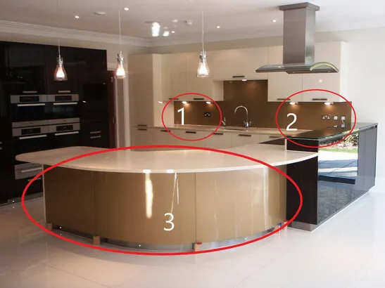 An image showing a kitchen  with multiple glass splashbacks which are the same colour but present darker or lighter in colour due to the differences between light sources.